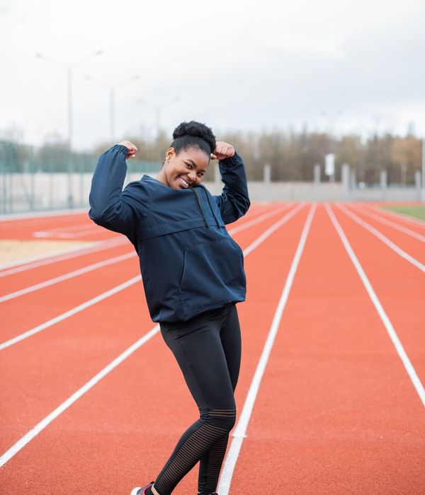 Smiling person stretching outdoors, conveying a sense of well-being and energy.